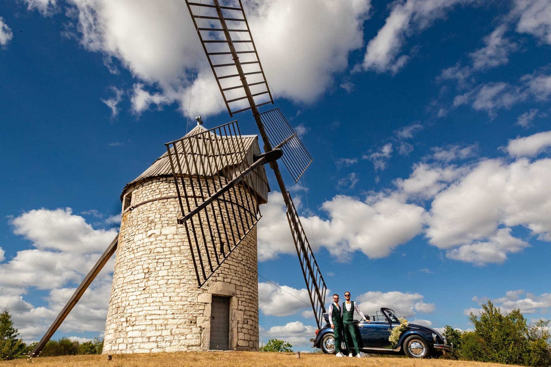 Couple de mariés devant un moulin avec une VW Cabriolet — photographe mariage 82