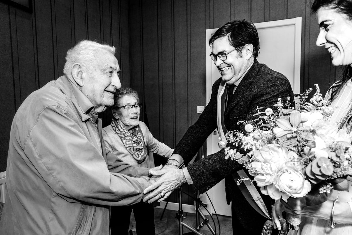 Rencontre émouvante entre les mariés et leurs grands-parents lors d'un mariage photographié en noir et blanc