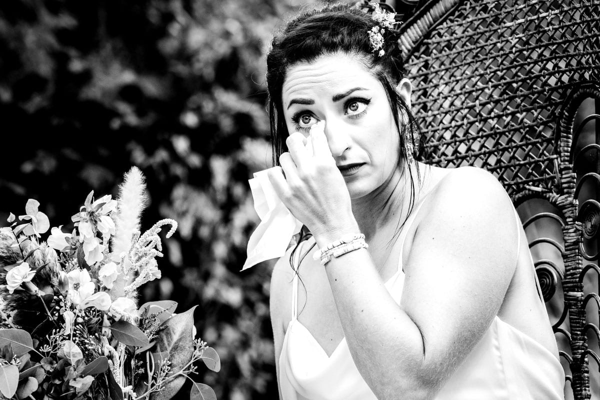 Mariée émue pendant les discours lors d'un mariage photographié en noir et blanc