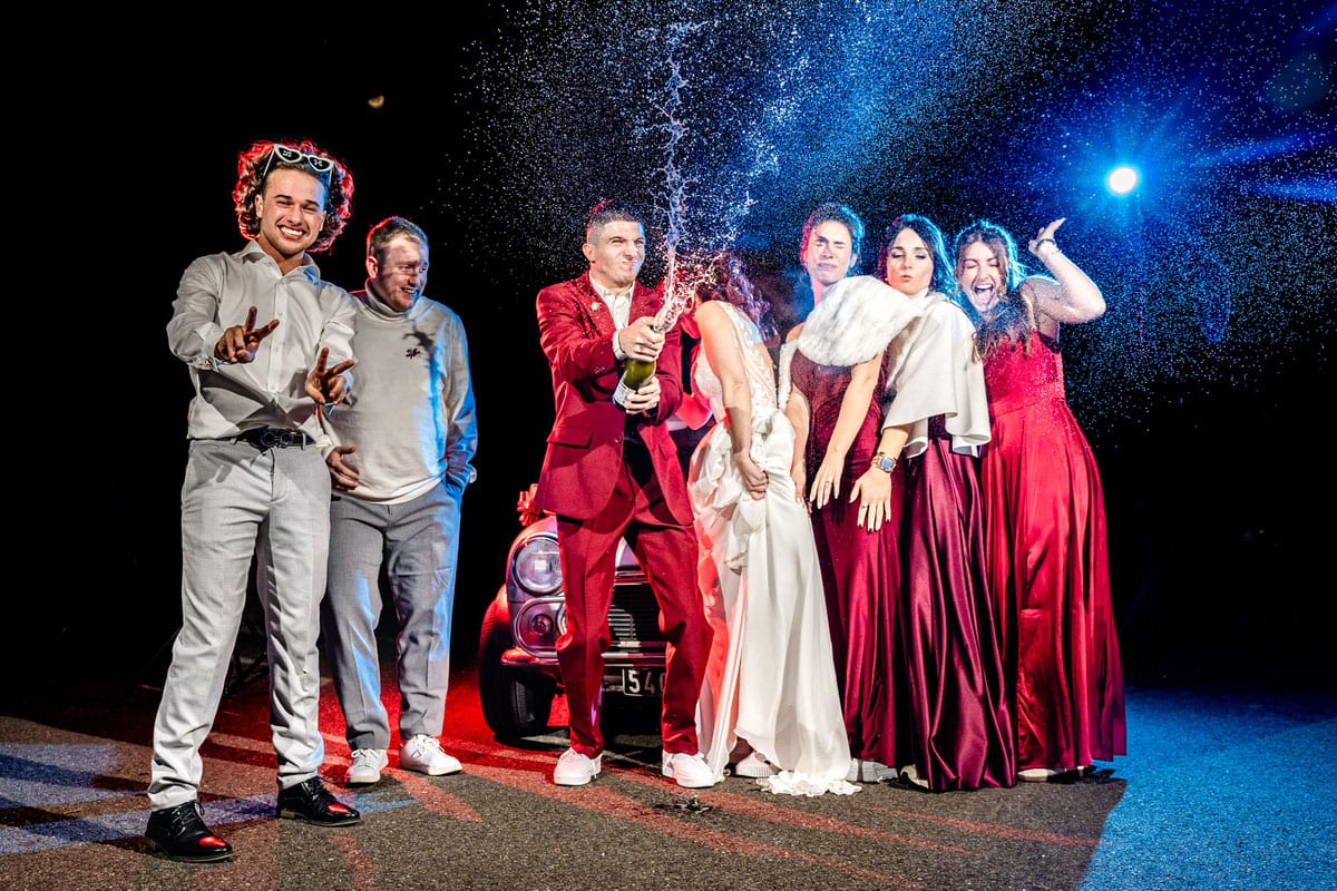 Photo de groupe originale de mariage avec mariés et invités dans une ambiance festive de nuit
